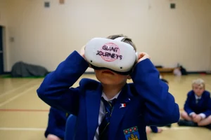 Landscape Still 05 Child in a blue blazer wearing a VR headset with "Giant Journeys" written on it.