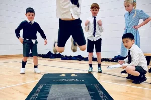 olympic jump 2 A child jumps on a measuring mat while other children watch and record results.